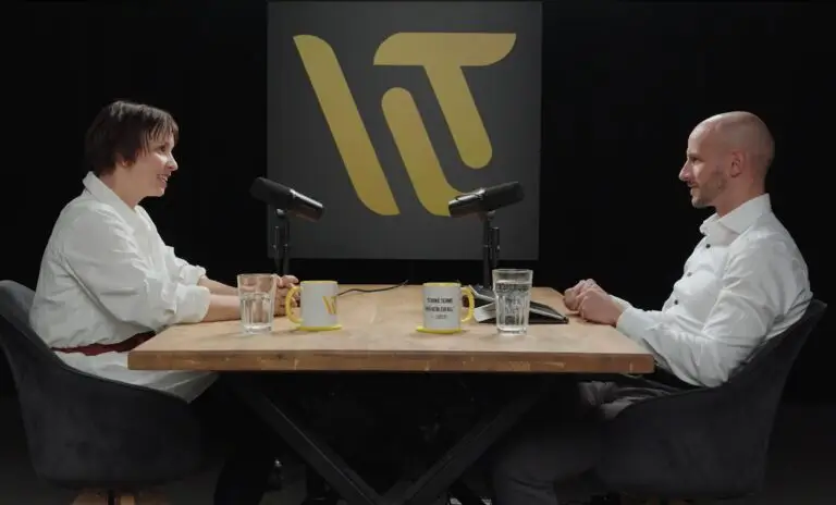 Zwei Experten im Podcast-Interview über Change Management im Unternehmen, sitzen an einem Holztisch mit Marken-Tassen und -Logo im Hintergrund.